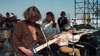 Movie still from “A Star Is Born” (1976), directed by Frank Pierson – A group of men playing instruments and singing; Medium shot, Low angle