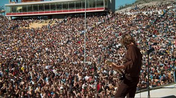 Movie still from “A Star Is Born” (1976), directed by Frank Pierson – A large crowd of people watching a man play a guitar; Extreme Wide shot, High angle