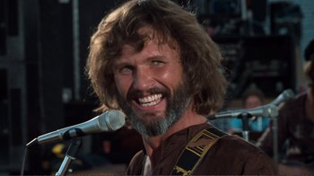 Movie still from “A Star Is Born” (1976), directed by Frank Pierson – A person with a beard and a microphone; Close Up shot, Low angle