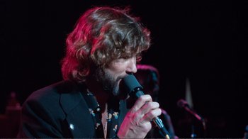 Movie still from “A Star Is Born” (1976), directed by Frank Pierson – A man with long hair is singing into a microphone; Close Up shot, Low angle