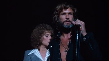 Movie still from “A Star Is Born” (1976), directed by Frank Pierson – A man and a woman standing next to a microphone; Close Up shot, Low angle