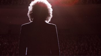 Movie still from “A Star Is Born” (1976), directed by Frank Pierson – A person standing in front of an audience at a concert; Medium shot, Low angle