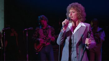 Movie still from “A Star Is Born” (1976), directed by Frank Pierson – A woman singing into a microphone on a stage; Medium shot, Low angle
