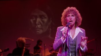 Movie still from “A Star Is Born” (1976), directed by Frank Pierson – A woman is singing into a microphone in front of an image of a woman; Medium shot, Low angle