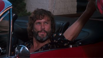Movie still from “A Star Is Born” (1976), directed by Frank Pierson – A man sitting in the back seat of a red car; Close Up shot, Low angle