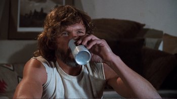 Movie still from “A Star Is Born” (1976), directed by Frank Pierson – A man drinking from a white cup while sitting on a couch; Medium shot, Low angle