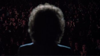 Movie still from “A Star Is Born” (1976), directed by Frank Pierson – A person is seen from behind in front of an audience; Medium shot, Low angle