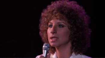 Movie still from “A Star Is Born” (1976), directed by Frank Pierson – A person holding a microphone; Close Up shot, High angle