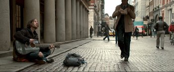 Movie still from “A Street Cat Named Bob” (2016), directed by Roger Spottiswoode – A person is walking down the street with a bag; Wide shot, Low angle