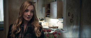 Movie still from “A Street Cat Named Bob” (2016), directed by Roger Spottiswoode – A woman standing in a kitchen next to a vase of flowers; Close Up shot, Over the shoulder angle