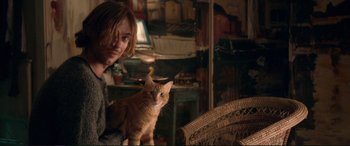Movie still from “A Street Cat Named Bob” (2016), directed by Roger Spottiswoode – A person holding a cat in a living room; Medium shot, Over the shoulder angle