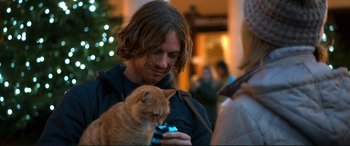 Movie still from “A Street Cat Named Bob” (2016), directed by Roger Spottiswoode – A man holding a cat while looking at a cell phone; Close Up shot, Over the shoulder angle