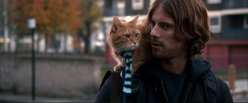 Movie still from “A Street Cat Named Bob” (2016), directed by Roger Spottiswoode – A man holding a cat on his shoulder; Close Up shot, Low angle