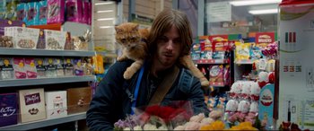 Movie still from “A Street Cat Named Bob” (2016), directed by Roger Spottiswoode – A man holding a cat on his shoulders; Medium shot, Over the shoulder angle