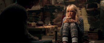 Movie still from “A Street Cat Named Bob” (2016), directed by Roger Spottiswoode – A woman sitting on the ground holding a cup; Medium shot, Over the shoulder angle