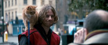 Movie still from “A Street Cat Named Bob” (2016), directed by Roger Spottiswoode – A man with long hair is holding an orange cat; Close Up shot, Over the shoulder angle