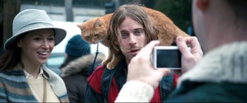 Movie still from “A Street Cat Named Bob” (2016), directed by Roger Spottiswoode – A man taking a picture with a cat on his shoulder; Close Up shot, Over the shoulder angle
