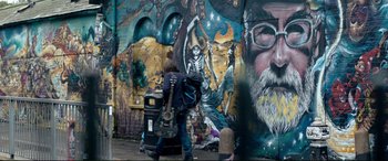 Movie still from “A Street Cat Named Bob” (2016), directed by Roger Spottiswoode – A man walking down a street next to a trash can; Wide shot, Low angle