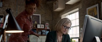 Movie still from “A Street Cat Named Bob” (2016), directed by Roger Spottiswoode – A woman sitting in front of another woman in front of a window; Medium shot, Over the shoulder angle