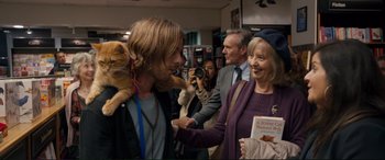 Movie still from “A Street Cat Named Bob” (2016), directed by Roger Spottiswoode – A man holding a cat on his shoulder and a woman; Medium shot, Over the shoulder angle