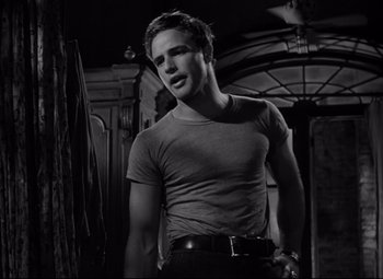 Movie still from “A Streetcar Named Desire” (1951), directed by Elia Kazan – Black and white photograph of a man in a t - shirt; Medium shot, Low angle