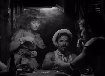 Movie still from “A Streetcar Named Desire” (1951), directed by Elia Kazan – A man sitting at a table in front of two women; Medium shot, Over the shoulder angle