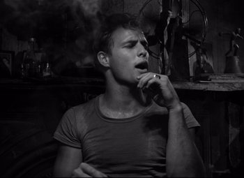 Movie still from “A Streetcar Named Desire” (1951), directed by Elia Kazan – A black and white photo of a man smoking a cigarette; Close Up shot, Low angle