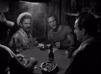 Movie still from “A Streetcar Named Desire” (1951), directed by Elia Kazan – A group of men sitting at a table with a beer; Medium shot, High angle