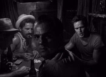 Movie still from “A Streetcar Named Desire” (1951), directed by Elia Kazan – A group of men sitting at a table with a beer; Medium shot, Over the shoulder angle