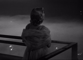 Movie still from “A Streetcar Named Desire” (1951), directed by Elia Kazan – A woman in a dress is standing on a balcony; Medium shot, High angle