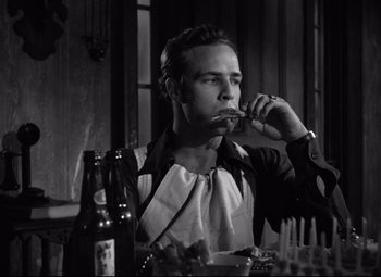 Movie still from “A Streetcar Named Desire” (1951), directed by Elia Kazan – A black and white photo of a man eating a sandwich; Medium shot, Low angle