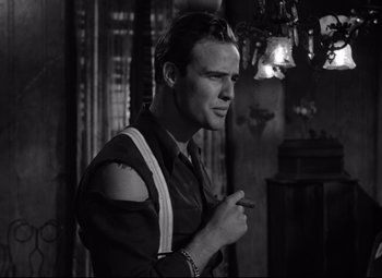 Movie still from “A Streetcar Named Desire” (1951), directed by Elia Kazan – A black and white photo of a man smoking a cigarette; Medium shot, Low angle