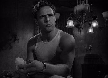 Movie still from “A Streetcar Named Desire” (1951), directed by Elia Kazan – A black and white photo of a man holding a piece of food; Close Up shot, Low angle