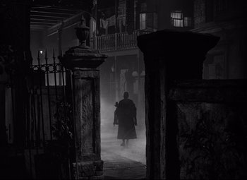 Movie still from “A Streetcar Named Desire” (1951), directed by Elia Kazan – A man walking through the fog in a dark place; Wide shot, Low angle