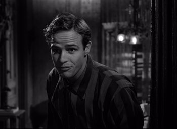 Movie still from “A Streetcar Named Desire” (1951), directed by Elia Kazan – Black and white photograph of a man in a striped shirt; Close Up shot, Over the shoulder angle