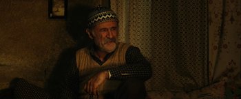 An older man wearing a hat and a sweater