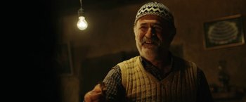 An older man wearing a hat and a sweater