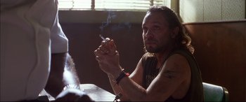 Movie still from “A Time to Kill” (1996), directed by Joel Schumacher – A man smoking a cigarette while sitting at a table; Close Up shot, Over the shoulder angle