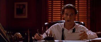 Movie still from “A Time to Kill” (1996), directed by Joel Schumacher – A man sitting at a desk in front of a laptop; Close Up shot, Low angle