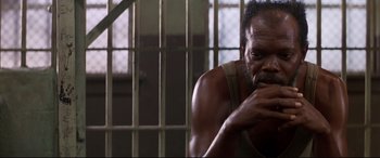 Movie still from “A Time to Kill” (1996), directed by Joel Schumacher – A man sitting in front of a metal gate; Close Up shot, High angle