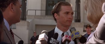 Movie still from “A Time to Kill” (1996), directed by Joel Schumacher – A person holding microphones on a city street; Close Up shot, Low angle