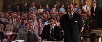Movie still from “A Time to Kill” (1996), directed by Joel Schumacher – A group of people sitting in front of an audience wearing suits; Medium shot, High angle