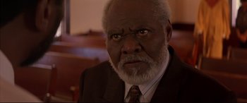 Movie still from “A Time to Kill” (1996), directed by Joel Schumacher – An older man in a suit and tie looking at the camera; Close Up shot, Low angle