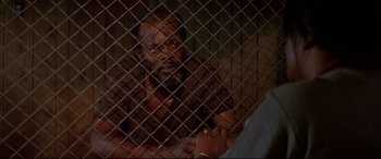 Movie still from “A Time to Kill” (1996), directed by Joel Schumacher – A man standing behind a metal fence looking at the camera; Close Up shot, Over the shoulder angle