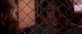 Movie still from “A Time to Kill” (1996), directed by Joel Schumacher – A woman sitting in front of a chain link fence; Close Up shot, Over the shoulder angle