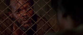 Movie still from “A Time to Kill” (1996), directed by Joel Schumacher – A person behind a chain link fence; Close Up shot, Over the shoulder angle