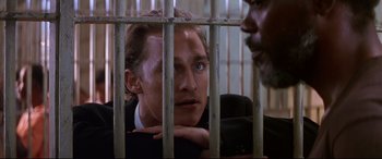 Movie still from “A Time to Kill” (1996), directed by Joel Schumacher – A man in a suit looking through a fence; Close Up shot, Over the shoulder angle