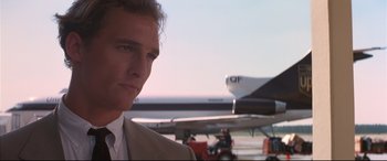 Movie still from “A Time to Kill” (1996), directed by Joel Schumacher – A man in a tan suit standing next to a plane; Close Up shot, Low angle