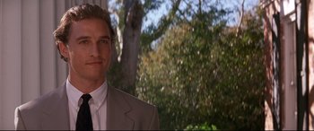 Movie still from “A Time to Kill” (1996), directed by Joel Schumacher – A man in a suit smiling for the camera; Close Up shot, Low angle