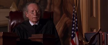 Movie still from “A Time to Kill” (1996), directed by Joel Schumacher – An old man sitting in front of an american flag in a courtroom; Close Up shot, Low angle